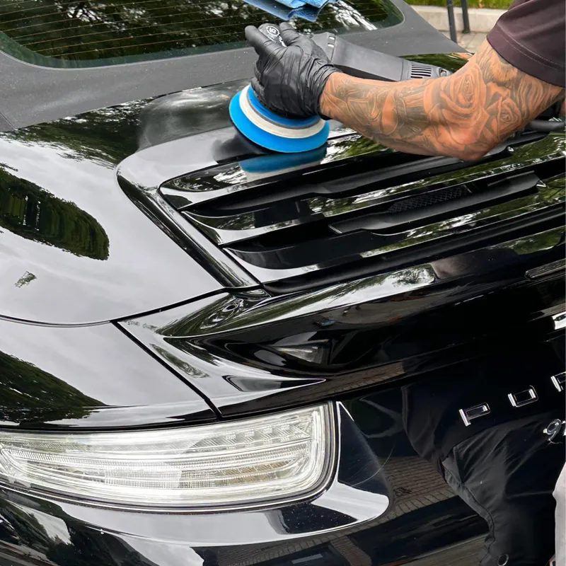 A detailer machine-polishing the black paint of a car