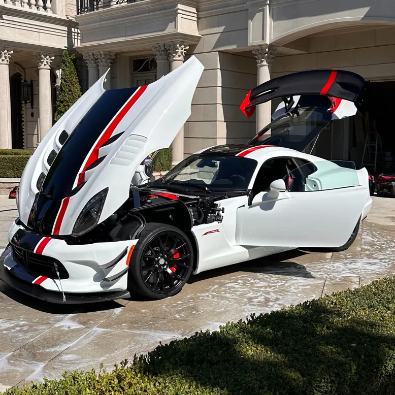 White Dodge Viper with the hood up during a wash